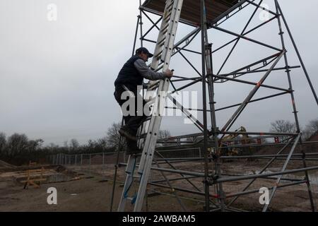 Ein Mann klettert auf ein Gerüst auf einer Verlängerungsleiter Stockfoto