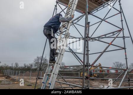 Ein Mann klettert auf ein Gerüst auf einer Verlängerungsleiter Stockfoto