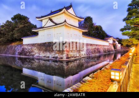 Eckbeobachtungsturm aus Steinmauern rund um die Burg Nijo in der Stadt Kyoto in Japan bei Sonnenaufgang mit Straßenbeleuchtung. Stockfoto