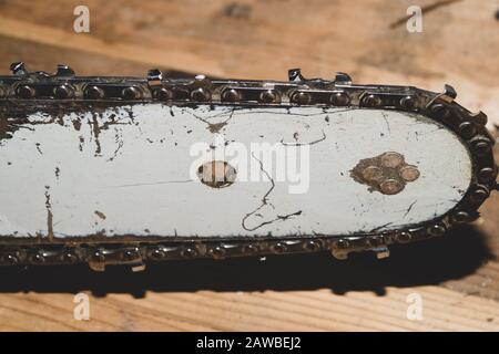 Kettensägebalken und Schneidekette schließen sich an. Blatt einer Kettensäge auf Holzhintergrund Stockfoto
