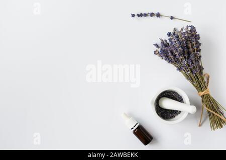 Flasche mit ätherischem Öl und Lavendelblüten auf weißem Hintergrund mit Freiraum für Text Stockfoto