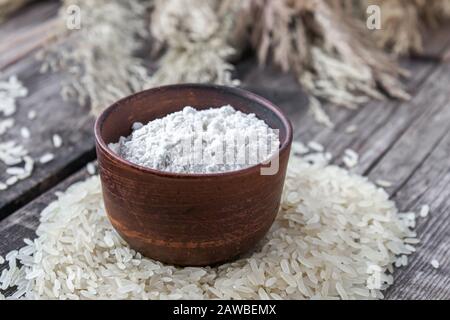 Reismehl in einer Schüssel auf einem Haufen weißem Reis auf alten Bretter. Jasminreis zum Kochen. Stockfoto