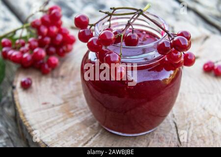 Viburnum-Fruchtstau in einem Glasbecher auf einem Holztisch in der Nähe der reifen roten Viburnum-Beeren. Quelle natürlicher Vitamine. In der Volksmedizin verwendet. Herbst harv Stockfoto