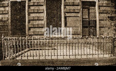 1921 gedrucktes Bild des Gehäuses des Schwarzen Lochs von Kalkutta (heute Kolkata) (innerhalb der Geländer). Das unter dem Boden liegende Verlies mit einer Größe von 4,30 × 5,50 ⁠meters (14 × 18 ⁠⁠feet) wurde von den Truppen Siraj ud-Daulahs, dem Nawab von Bengalen, drei Tage lang britische Kriegsgefangene gefangen gehalten. Es befindet sich in Fort William, Kalkutta, Indien. 123 von 146 Kriegsgefangenen, die in schrecklich beengten Verhältnissen inhaftiert waren, starben dort. In Erinnerung an die Toten errichteten die Briten einen 15 Meter hohen Obelisken, der sich heute auf dem Friedhof der (anglikanischen) St. John's Church in Kalkutta befindet Stockfoto