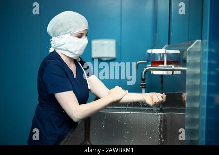 Der Chirurgenarzt in der medizinischen Maske desinfiziert die Hände vor der Operation. Stockfoto