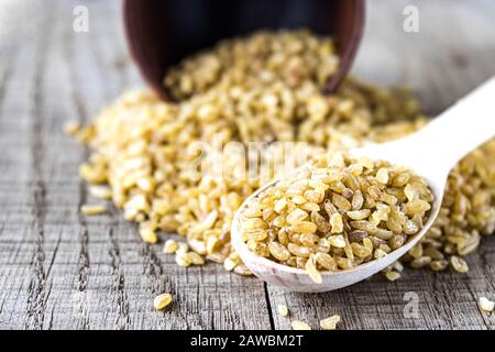 Trockenes Bulgur in einem Holzlöffel. Gesundes, diätetisches, veganes, glutenfreies Produkt. Stockfoto