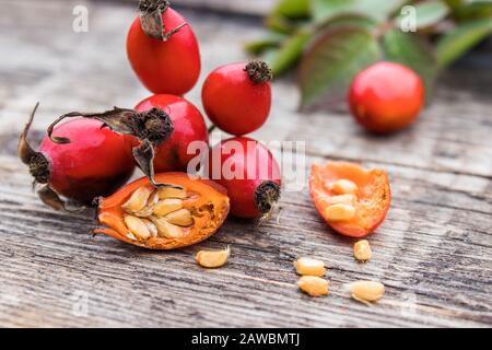 Rote Rosehips und halbiert Beeren mit Samen auf einem Holztisch. Nahaufnahme. Stockfoto