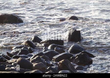 Steine im Schaum haben Wasser geköpft Stockfoto