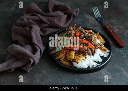 Kubanische, geschredderte Rindfleisch. lateinamerikanische Küche. Ropa Vieja mit gebratenen Kochbananen und Reis. Carne desmechada, Carne desmenuzada, Carne mechada Stockfoto