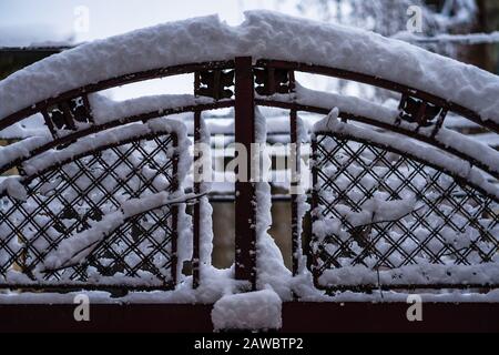 Drahtzaun und metallisches Netz mit Schnee. Metallnetz im Winter mit Schnee bedeckt. Stockfoto