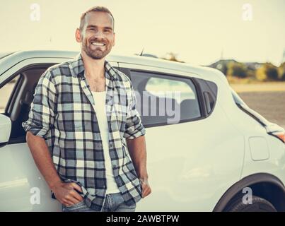 Eine attraktive junge Mann steht in der Nähe ein Auto. Stockfoto