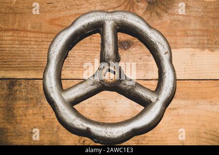 Vintage-Ventil auf Holzhintergrund, Stahlradventil auf dem Tisch. Industrieller Hintergrund Stockfoto