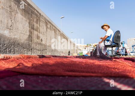 Fischer reparieren Fischernetze auf der Quayside im Hafen von Playa San Juan, auf Tenera, auf den Kanarischen Inseln, in Spanien Stockfoto