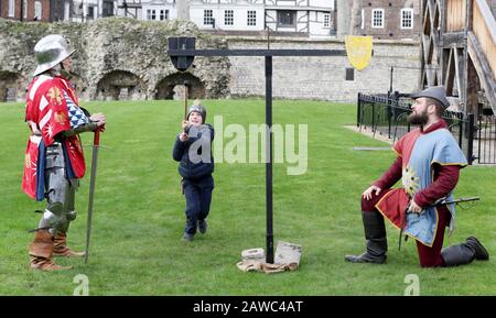 Ranulph Robins, 7, nähert sich einem Reenactor, der als Sir Anthony Woodbridge (links) und sein Squire Roger (rechts) verkleidet ist, während er einen Chintain mit einer Lanze in einer Pressevorschau für die Knight School am Tower of London in der City of London angreift. Stockfoto