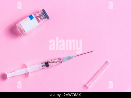Spritze mit Impfstofftropfen mit Impfstoff In Der Durchstechflasche über rosafarbenem Hintergrund. Impfung mit medizinischem Konzept Hypodermic Injection. Immunisierung bei der Vorbeugung von Behandlungen Stockfoto