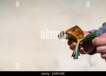 Mann Hand rechnet Geld für Bestechung oder Trinkgeld. Die Euro-Banknoten auf einem verschwommenen Hintergrund zu halten, die EURO-WÄHRUNG Stockfoto