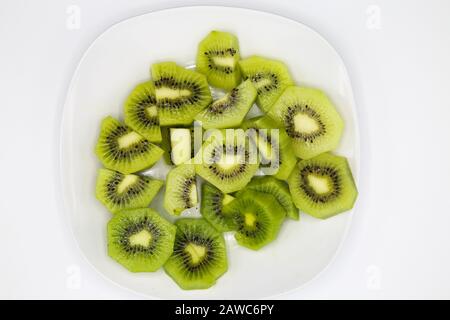 Hochwinkelige Ansicht auf Gruppe geschnitten frisch grün glänzende Kiwifrüchte auf weißem Teller Stockfoto