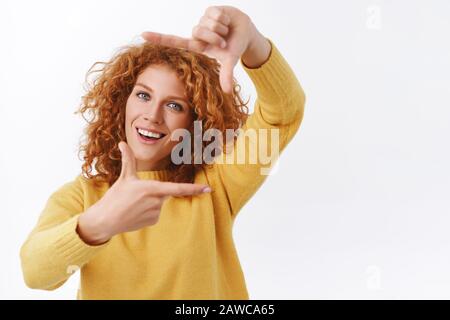 Taillen-Up-Porträt, kreativ gut aussehende rotkopfige Frau in gelbem Pullover, Fotograf oder Designer suchen perfekten Winkel-Look aus der Perspektive Stockfoto