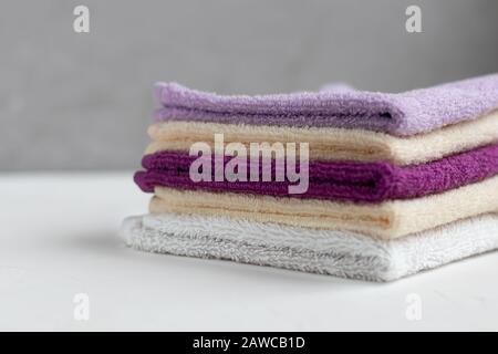 Frottee-Handtücher für Schönheit und Gesundheit. Ein Stapel mehrfarbiger Handtücher liegt auf weißem Hintergrund. Lifestyle, Hausarbeit. Kopierbereich. Stockfoto