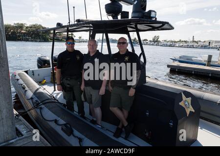 Die Abgeordneten Michael Joseph und Pete Peterson posieren mit einem Touristen auf der Manatee Pocket im Sandsprit Park in Port Salerno, Florida, USA. Stockfoto