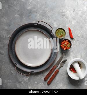 Kolumbianische Küche, aji picante, hogao salsa, auf der Metallschale und Zutaten für Souce, auf der grauen Betonkulisse, Platz für Designtext Stockfoto