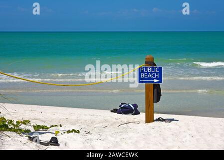Ein blaues Schild am öffentlichen Strand auf einer Stange mit einem Pfeil nach rechts und Gelb Stockfoto