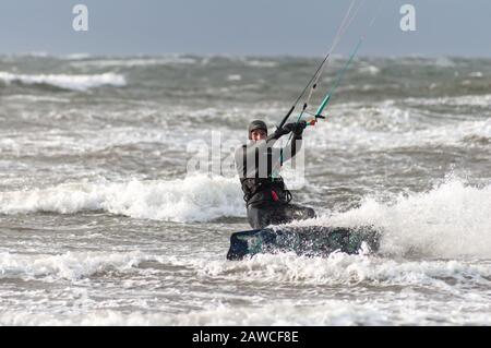 Troon, Schottland, Großbritannien. Februar 2020. Wetter in Großbritannien: Ein Kitesurfer, der die Brandung genießt, während Storm Ciara in South Beach ankommt, Troon mit starkem Regen und Wind, die voraussichtlich 70 bis 85 mph erreichen werden. Das MET-Büro hat in ganz Großbritannien eine gelbe Wetterwarnung herausgegeben. Kredit: Skully/Alamy Live News Stockfoto