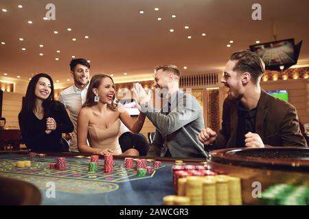 Fröhliche Gruppe von Freunden genießt Winning Poker Roulette in einem Casino. Stockfoto