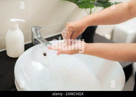 Waschen der Hände der Frau mit Seife unter dem Kran mit Wasser Stockfoto