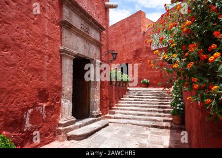 Enge Straße mit dem Bogen des Klosters Santa Catalina, Arequipa, Peru, hat Blumen herumgeschüttet. Stockfoto