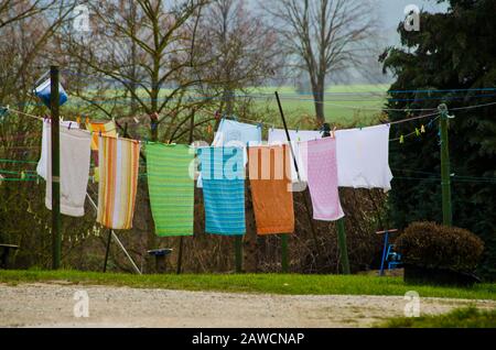Viele bunte Handtücher und Waschsalon hängen an einer Kleidungslinie in einem Innenhof eines alten Bauernhauses Stockfoto