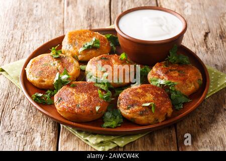 Straßennahrung Indiens. Kartoffel Aloo Tikki serviert mit Joghurt in einem Teller auf dem Tisch. Horizontal Stockfoto
