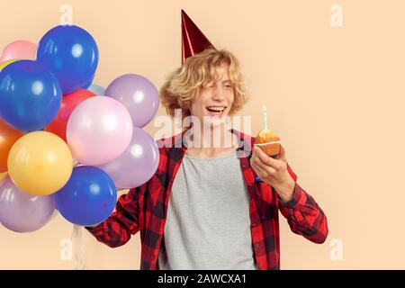 Junger Mann, der Cupcake mit Kerze in den Händen hält Stockfoto