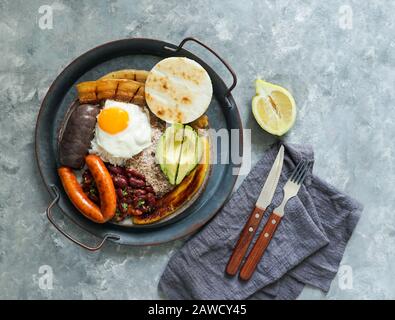 Kolumbianische Küche. Bandeja Paisa, typisches Gericht in der Region Antioquia in Kolumbien - Chicharron (gebratener Schweinebauch), schwarzer Pudding, Wurst, Arepa, Bohnen, Stockfoto