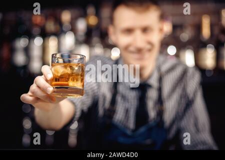 Barman hält Glas Whisky mit Eis für männliche Besucher aus. Konzeptruhe in der Bar. Stockfoto