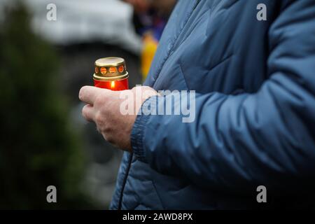 Flache Schärfentiefe (selektiver Fokus) mit den Händen eines Mannes, der an einem regnerischen kalten Tag eine Kerze im Freien hält. Stockfoto