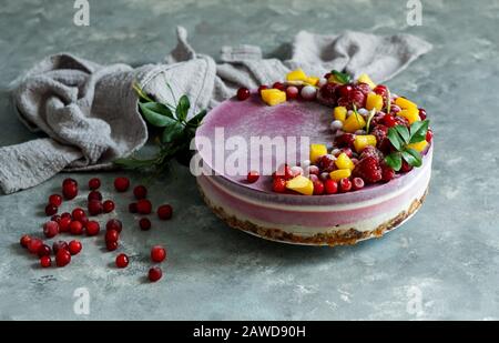 Veganer roher Käsekuchen mit Blaubeere, Kirsche, Matchtee, Orange, Cashew-Creme, Kokosbutter und Kokosmilch sowie Basis aus Mandeln, Datteln und Stockfoto