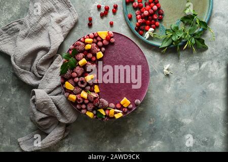 Veganer roher Käsekuchen mit Blaubeere, Kirsche, Matchtee, Orange, Cashew-Creme, Kokosbutter und Kokosmilch sowie Basis aus Mandeln, Datteln und Stockfoto