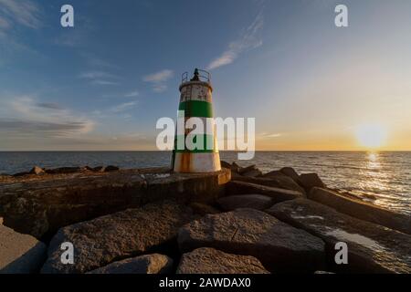 Pier und Leuchtturm am Eingang zum Hafen Portimao in der Region Algarve in Portugal in der Abenddämmerung Stockfoto