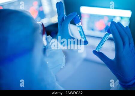 Forschungswissenschaftlerin verwendet Computerblut-Reagenzgläser im modernen Labor. Blaue Farbe, Virus-Epidemie. Stockfoto