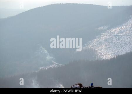 08. Februar 2020, Sachsen-Anhalt, Wernigerode: Ein Tourist sitzt auf einem Felsen auf dem Brockengipfel. Das Wetter im Harz dürfte sich in den kommenden Tagen grundlegend ändern. In der Nacht zum Montag erreicht ein Sturmtief die Region. Dann kann der Wind auch im Tiefland Hurrikankraft erreichen. Foto: Klaus-Dietmar Gabbert / dpa-Zentralbild / ZB Stockfoto