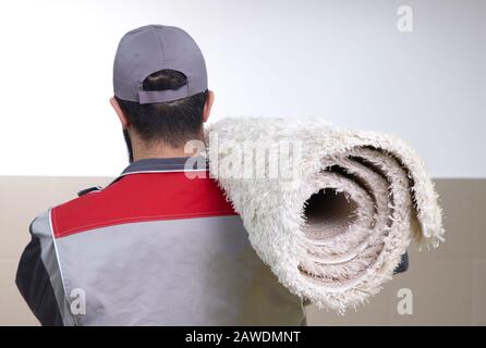 Rückansicht des Menschen mit einer Rolle Teppich auf einer Schulter Stockfoto