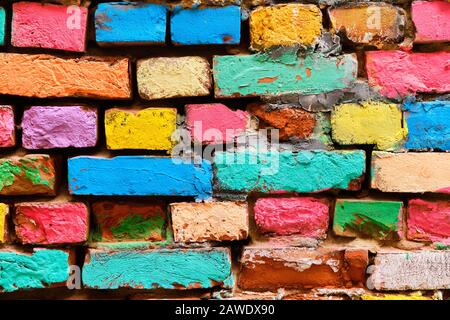 Zerfallende Ziegelwand in verschiedenen Farben bemalt. Nahaufnahme. Stockfoto