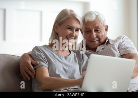 Modernes, reifes Paar, das sich zu Hause mit einem Laptop entspannen kann Stockfoto