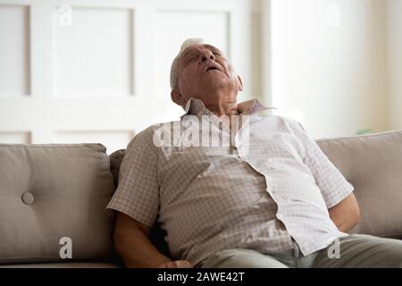 Erschöpfter älterer Mann schläft zu Hause auf der Couch ein Stockfoto