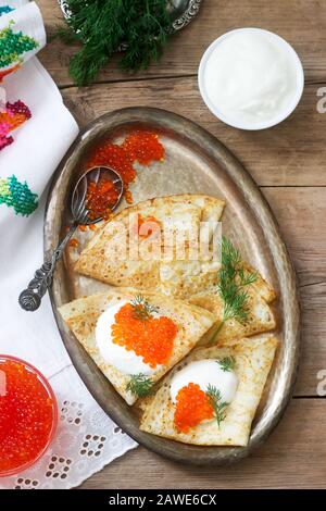 Hausgemachte Pfannkuchen mit rotem Kaviar, saurer Sahne und Dill serviert mit Wodka. Rustikaler Stil. Stockfoto