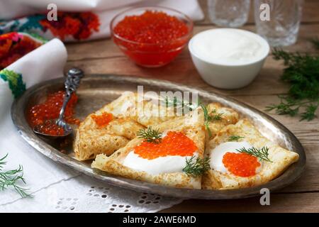 Hausgemachte Pfannkuchen mit rotem Kaviar, saurer Sahne und Dill serviert mit Wodka. Rustikaler Stil. Stockfoto