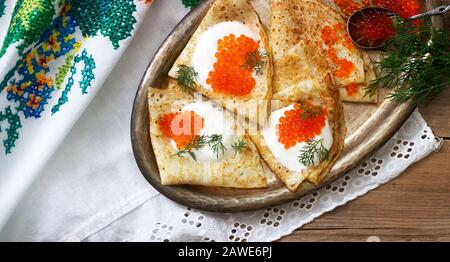 Hausgemachte Pfannkuchen mit rotem Kaviar, saurer Sahne und Dill serviert mit Wodka. Rustikaler Stil. Stockfoto