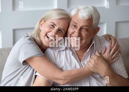 Kopfschussporträt des fröhlichen älteren Paares, das sich umarmt Stockfoto