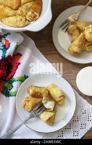 Hausgemachte Pfannkuchen, gefüllt mit Hüttenkäse mit Rosinen, serviert mit Sauerrahm und Kirsche. Stockfoto